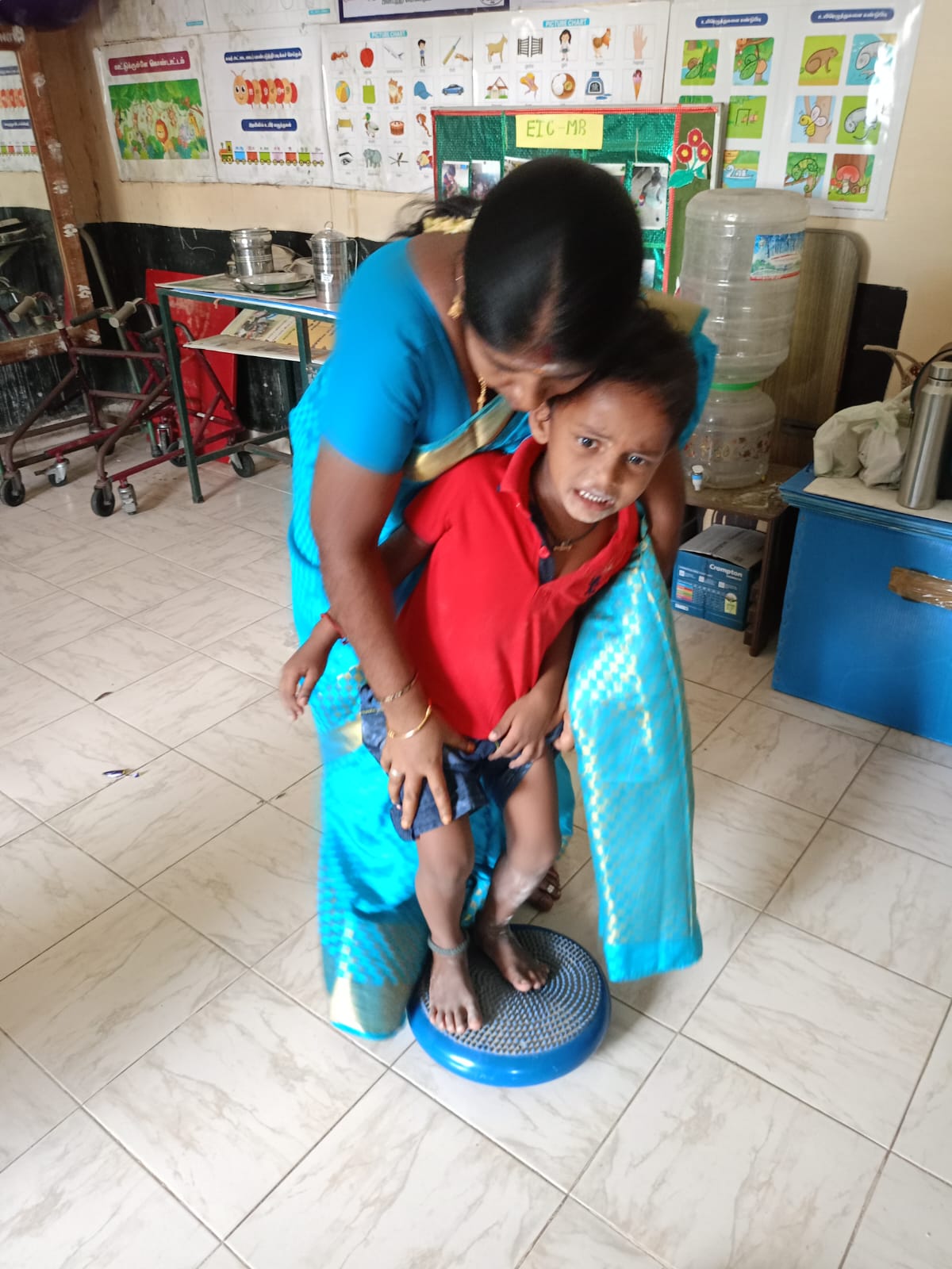 Teacher guiding children during an activity at Manolayam
